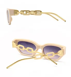 Detail of cream frame sunglasses with golden chain temples and gradient lenses