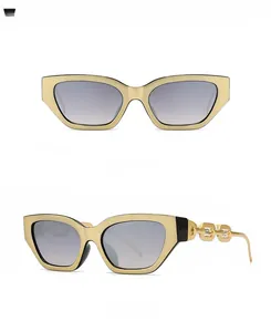 Detail view of narrow rectangular sunglasses with bold gold chain link arms and gray lenses