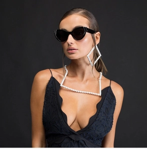 Détail macro de lunettes de soleil œil-de-chat noires et parure de bijoux en perles