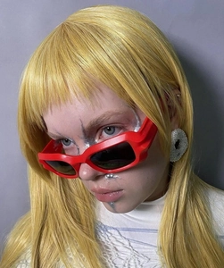 Close-up of model wearing bold red rectangular sunglasses with dark lenses for street style