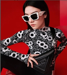 Détail de lunettes de soleil œil-de-chat blanches et sac en cuir noir sur fond rouge