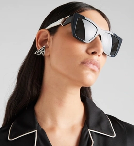 Detail of black rectangular sunglasses with metal accents and triangular enamel earrings