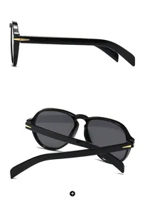 Detail of black aviator sunglasses featuring a golden arrow metal hinge accent