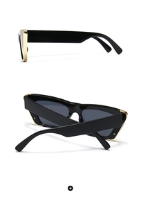 Detail view of square black sunglasses with golden metal trim and dark grey lenses