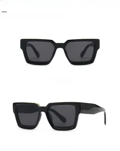 Detail of square black sunglasses with gold metal trim and integrated nose pads