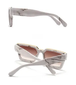 Detail of white marble frame sunglasses with gold top bar and sleek brown gradient lenses