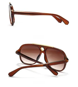 Detail of pilot sunglasses with brown gradient lenses and gold metal top bar and nose piece