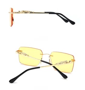 Detail view of gold panther relief decoration on temples of frameless orange sunglasses