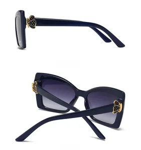 Détail de lunettes de soleil oversize avec charnières papillon dorées et verres dégradés