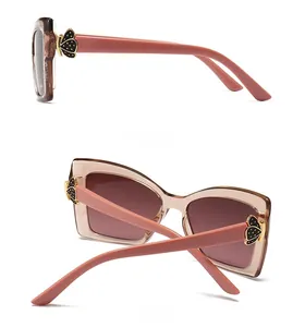 Détail de lunettes de soleil œil de chat marron rose avec charnières papillon dorées