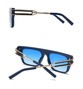 Detail view of square sunglasses with blue gradient lenses and golden C-shaped metal hinge