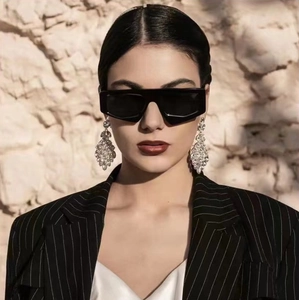 Close-up of stylish bold black geometric sunglasses and silver rhinestone fringe earrings