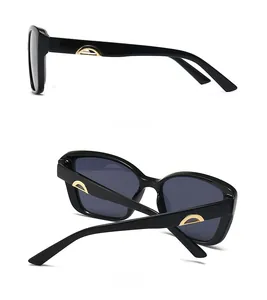 Detail view of black square sunglasses showing side gold metal trim and back folding hinges