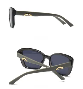 Detail view of large frame sunglasses with grey-green matte temples and gold curved accents