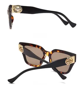 Detail view of tortoiseshell oversized sunglasses featuring a golden geometric logo on temples