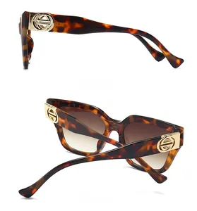 Detail view of tortoiseshell cat-eye sunglasses with golden metal hinge ornaments