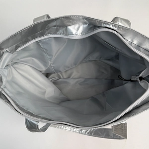 Detailed interior view of a silver tote bag with gray lining and a side pocket storage