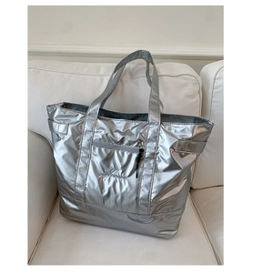 Detail of silver metallic tote bag featuring fine embroidery and front zipper pocket