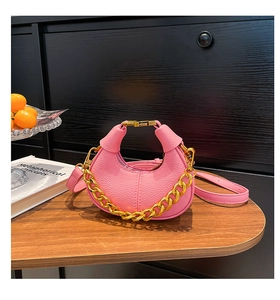 Detailed macro view of a pink crescent mini bag with textured leather and gold chain
