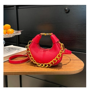 Macro detail of lychee grain leather handbag with gold metal clasp and chunky chain