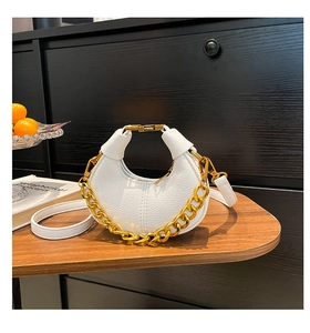 Detail of white lychee leather crescent bag featuring a bold chunky gold chain strap