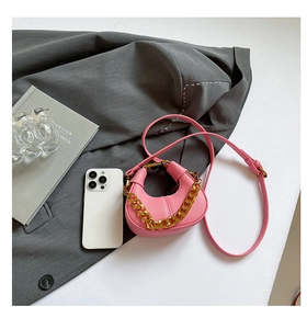 Pink crescent mini bag with gold chain strap shown next to a smartphone for size scale