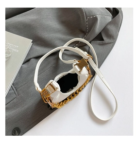 Detail view of mini white leather crescent bag with golden chain and zip closure