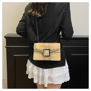 Détail de la texture serpent du sac avec boucle en métal noir et bandoulière chaîne