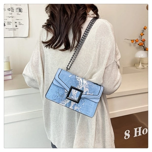 Détail du sac bandoulière bleu motif serpent avec boucle noire porté par le modèle