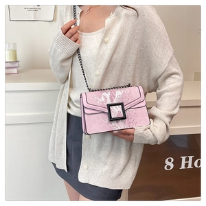 Sac bandoulière rose à motif serpent et chaîne porté par un mannequin