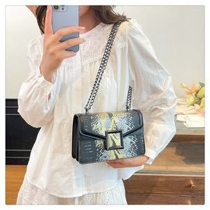 Détail du sac bandoulière en cuir noir avec imprimé serpent et bandoulière en chaîne