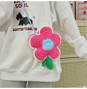Détail d'un sac à fleurs crocheté à la main avec cœur bleu et pétales roses