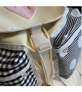 Detail of durable white plastic buckle and pink heart charm on canvas backpack