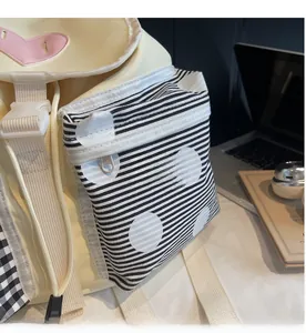 Detail view of canvas backpack featuring pink heart patch and striped polka dot front pocket