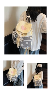 Detail of cute beige canvas backpack featuring pink heart and mixed pattern side pockets