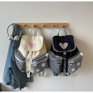 Detail view of heart patch and checkered pocket on minimalist canvas backpacks