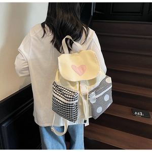 Close-up of heart embroidery and multi-pattern pockets on a beige canvas backpack