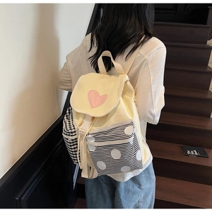 Detail of canvas backpack featuring pink heart patch and contrast geometric patterned pockets