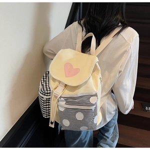 Detail view of canvas backpack with pink heart patch and black-white patterned side pockets