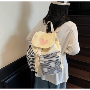 Detail of canvas backpack featuring pink heart patch and contrast patterned front pockets