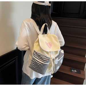 Detail of canvas backpack with heart embroidery and checkered pockets on stairs