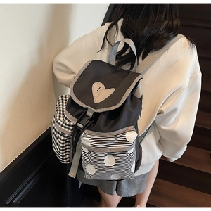 Detail view of stylish multi-pattern backpack featuring heart patch and checkered side pocket