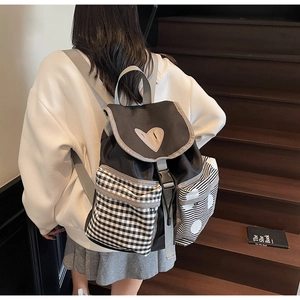 Detailed view of canvas backpack featuring heart emblem and mixed pattern front pockets
