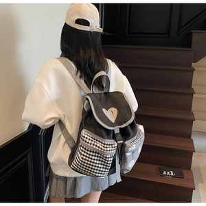 Detail of canvas backpack featuring heart decor and striped pockets on wooden stairs