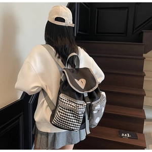 Detail of preppy black backpack with checkered pockets and heart patch on stairs