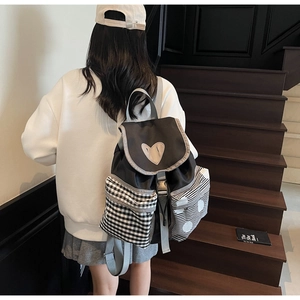Detail of black backpack featuring heart patch and asymmetrical patterned side pockets
