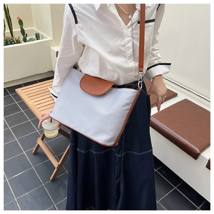 Detail of light blue tote bag with brown leather trim and metal hook strap attachment