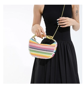 Détail d'un sac demi-lune tissé à rayures colorées avec une poignée en métal doré