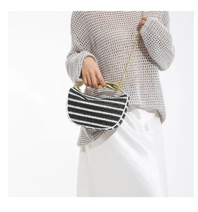 Détail du sac tissé à rayures noires et blanches avec poignée dorée et bandoulière