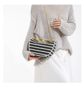Détail du sac tissé à rayures noires et blanches avec poignée dorée et bandoulière
